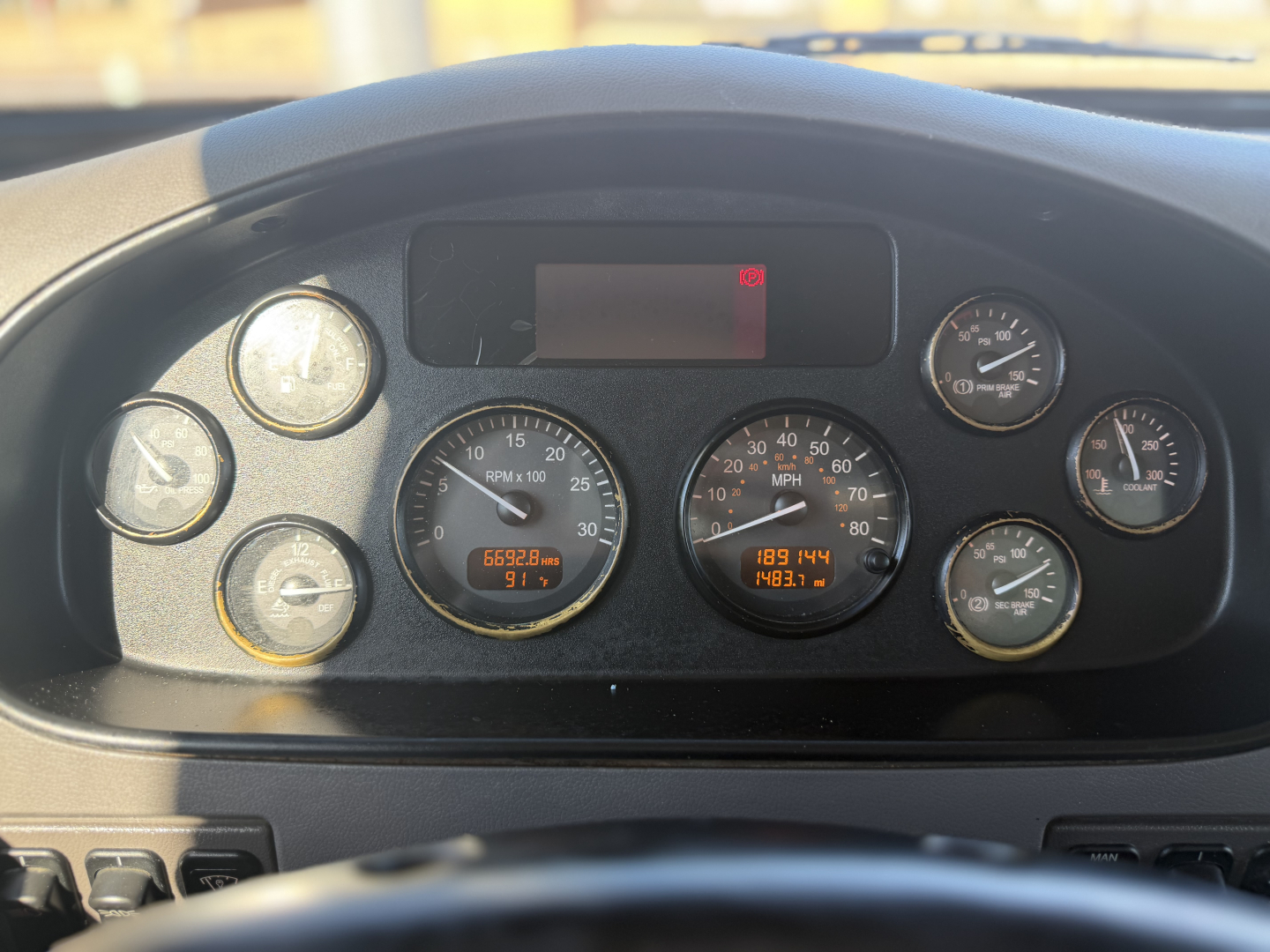 Dashboard of a Peterbilt 337 truck showing multiple gauges including speedometer, tachometer, fuel, and digital readouts; steering wheel bottom edge visible.