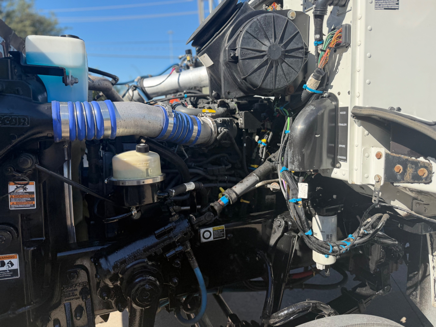 Peterbilt 337 engine bay showing coolant reservoir, hoses, and electrical harnesses.