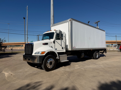 Peterbilt 337 box truck in a parking lot with a white cab and a large box, front grille and headlights visible.