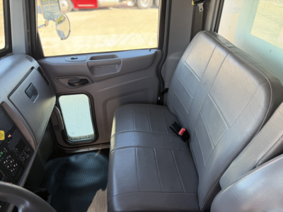 Peterbilt 337 cab interior with gray bench seat and dashboard, front door panel and window.