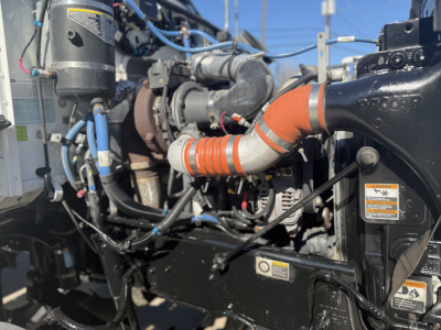 Peterbilt engine bay showing orange coolant hose, black radiator/turbo housing, wiring harness, and various labels/stickers.