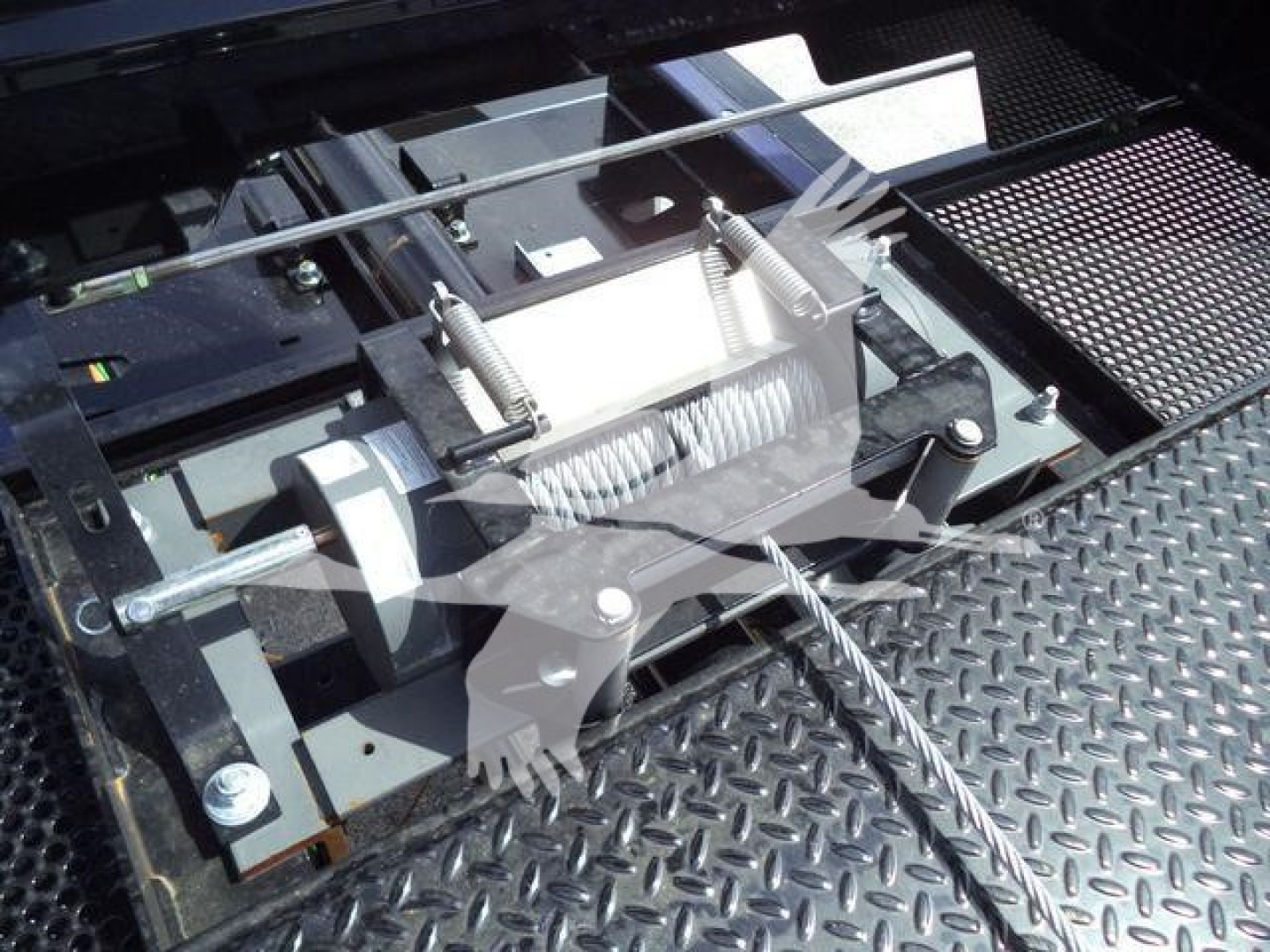 Trucks equipment component showing a winch or hydraulic cable reel assembly with spring-loaded cable tensioners on a diamond plate platform.