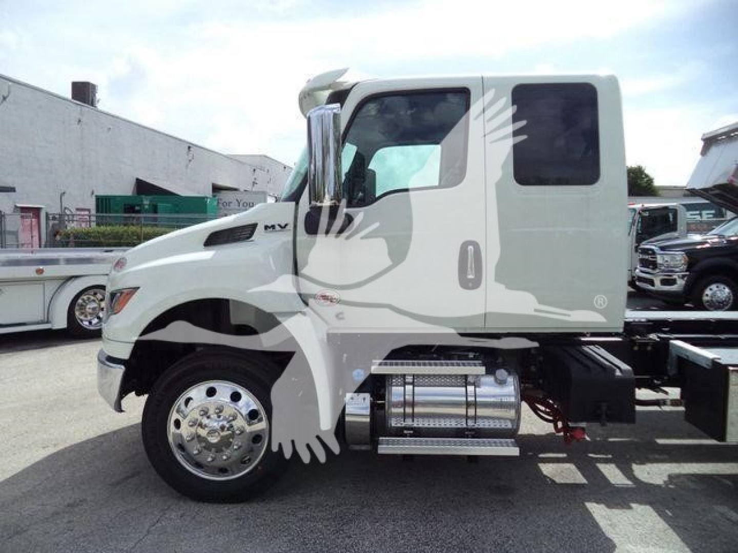 Truck cab side view showing International MV 7/8 with fuel tanks and chrome wheels.