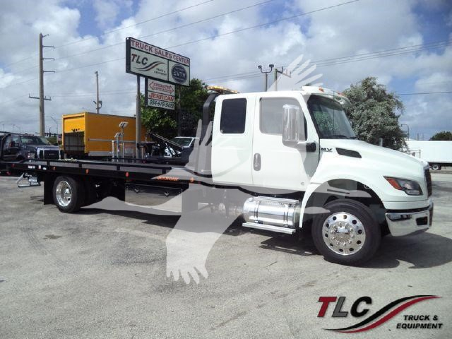 Truck cab and rollback flatbed with white exterior and chrome fuel tanks, side view showing flatbed and wheels.