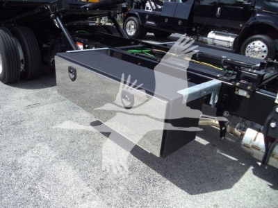 Flatbed toolbox mounted on truck chassis with side handle and latch, undercarriage and fuel tank visible