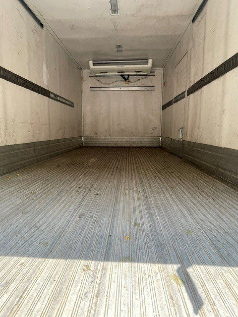 Isuzu NQR cargo box interior showing empty aluminum floor and side rails, rear entry, ceiling vent, and refrigeration unit at front of truck box.