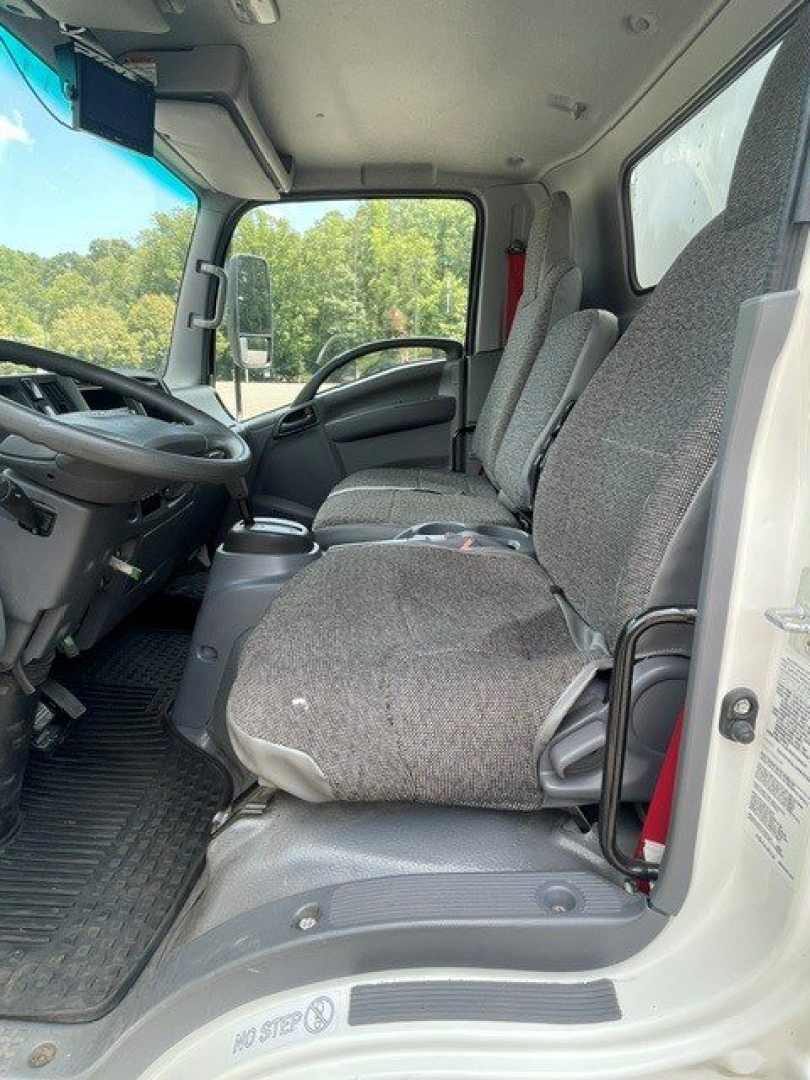 Isuzu NQR cab interior showing driver and passenger seats, steering wheel, and dashboard in view.