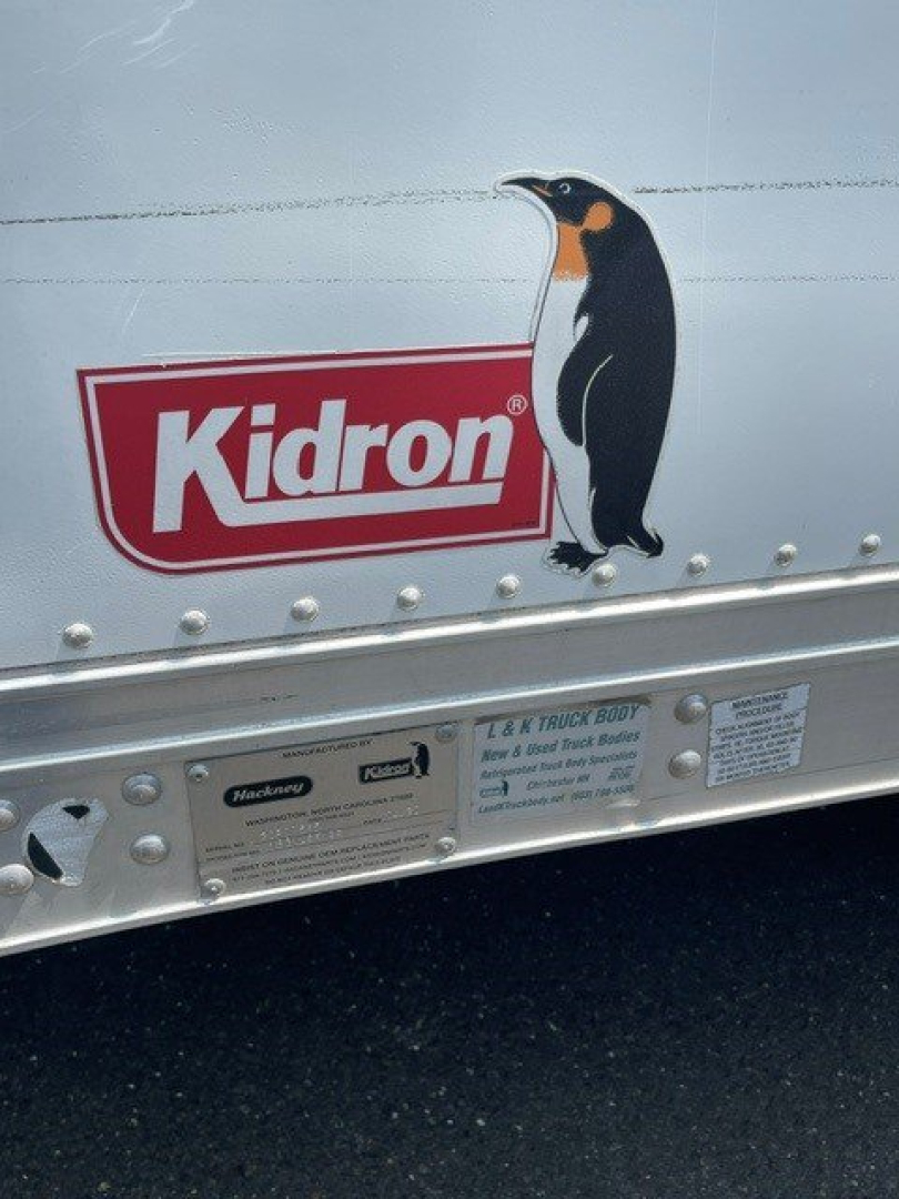 Box van side showing Kidron logo and penguin graphic on metal surface with small informational plate.