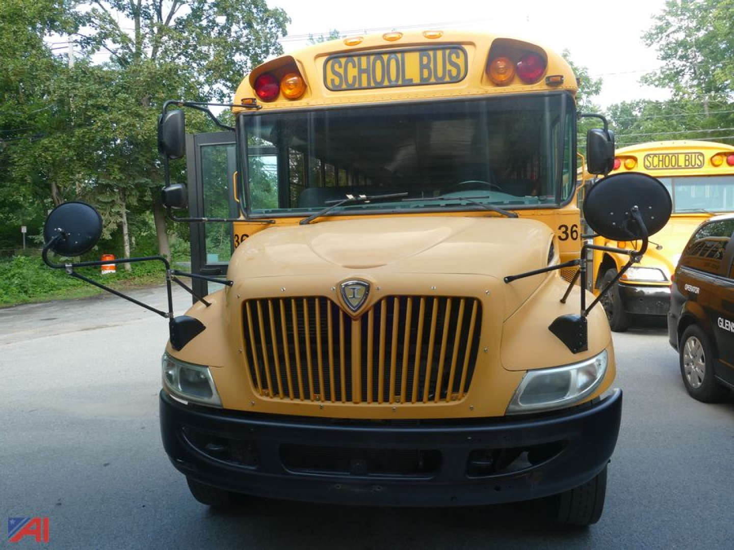 School bus front view with wheelchair lift integration and 'SCHOOL BUS' sign on top, beige body, large grille, round mirrors.