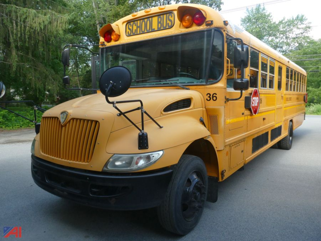 School bus with wheelchair lift and stop sign on the side, front-facing view of a yellow IC Corporation CE series bus, bus number 36, hood and mirrors visible.
