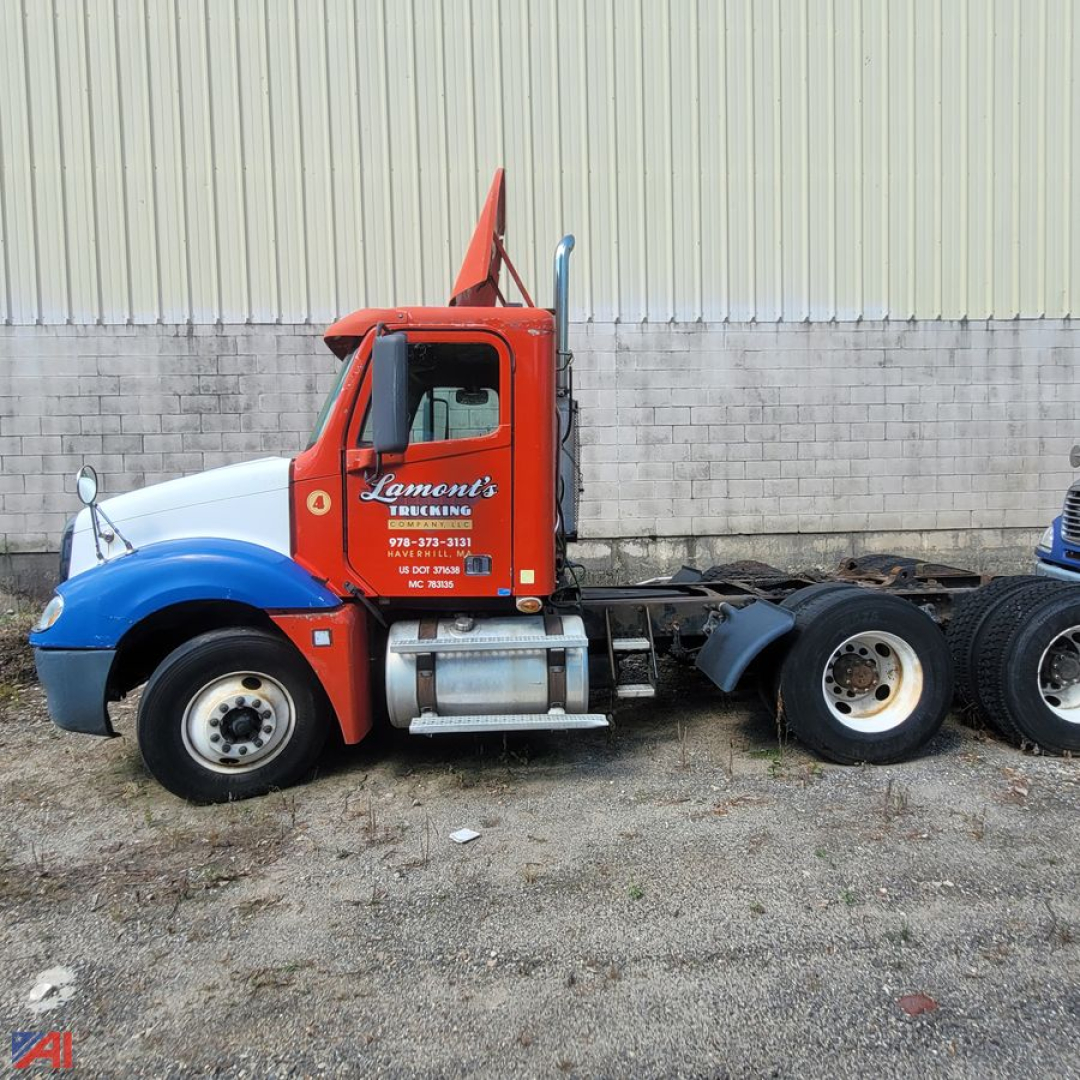 Truck cab side view showing red Lament's Express truck with blue fenders and Freightliner Columbia 120 chassis, labeling on door, fuel tank, exhaust stack, and dual rear wheels.