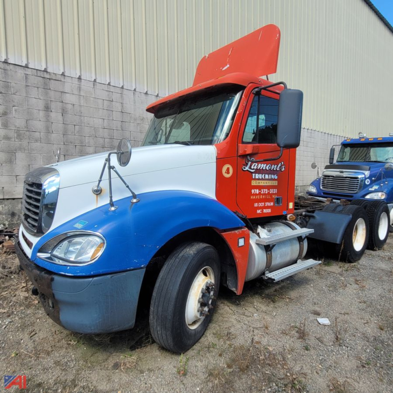 Freightliner Columbia 120 conventional truck in yard showing blue lower body and red cab with raised hood and side mirrors.