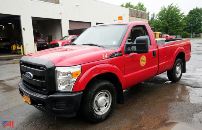Ford F-250 Super Duty XL single-cab pickup with toolbox in bed, red exterior, black grille, front left view, company logo on door, orange beacon on roof.