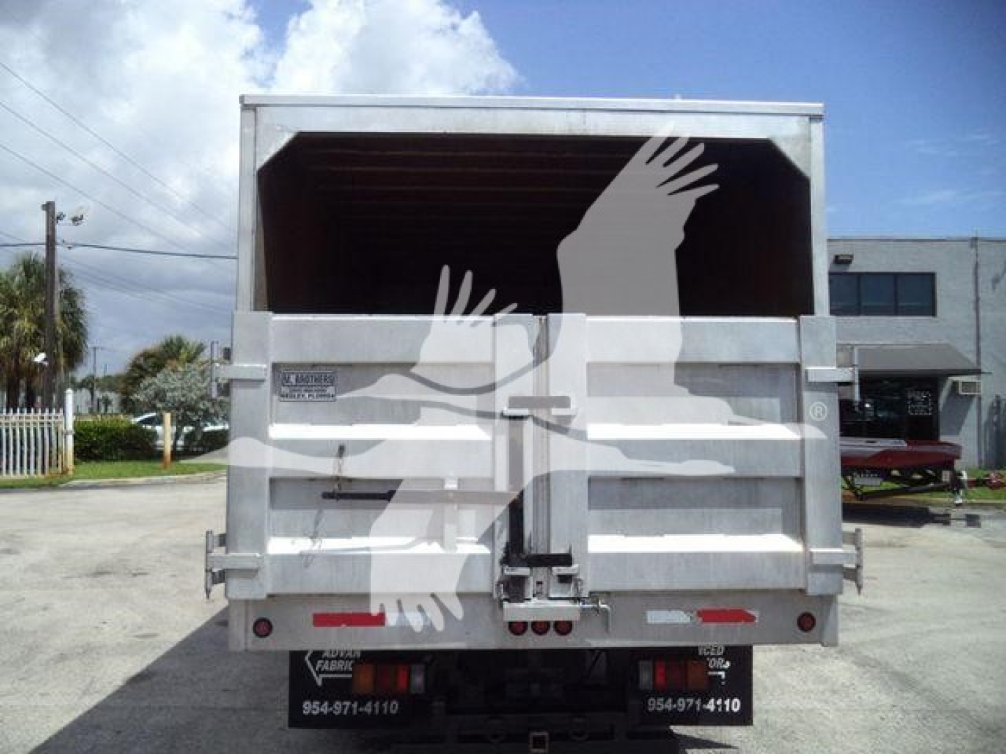 Back of Isuzu NPR/XD dump truck showing tailgate latch and rear lights, with open cargo bed.