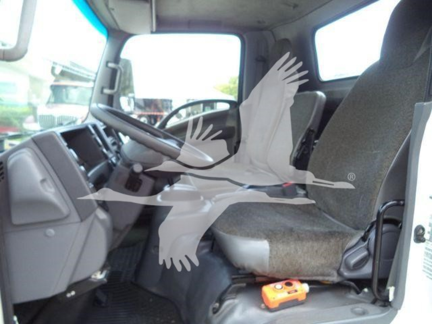 Isuzu NPR-XD truck cabin interior showing driver seat and passenger seat with steering wheel and dashboard.
