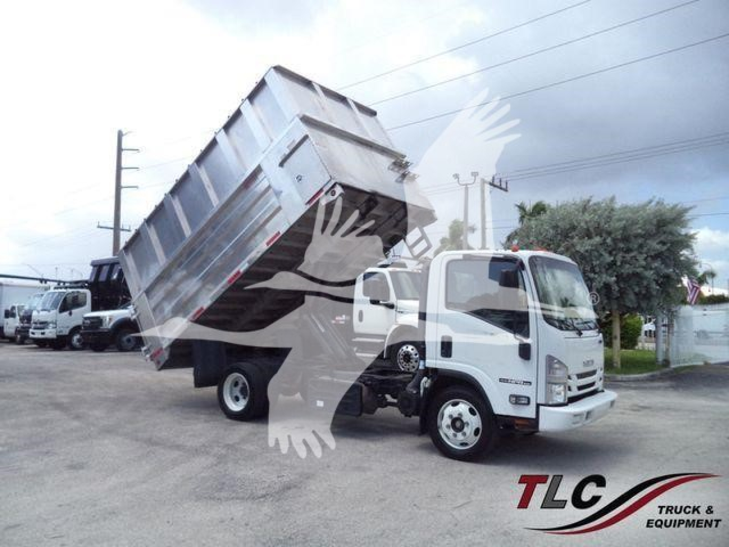 Isuzu NPR XD truck with dump bed tilted up in a lot, showing chassis and cab.