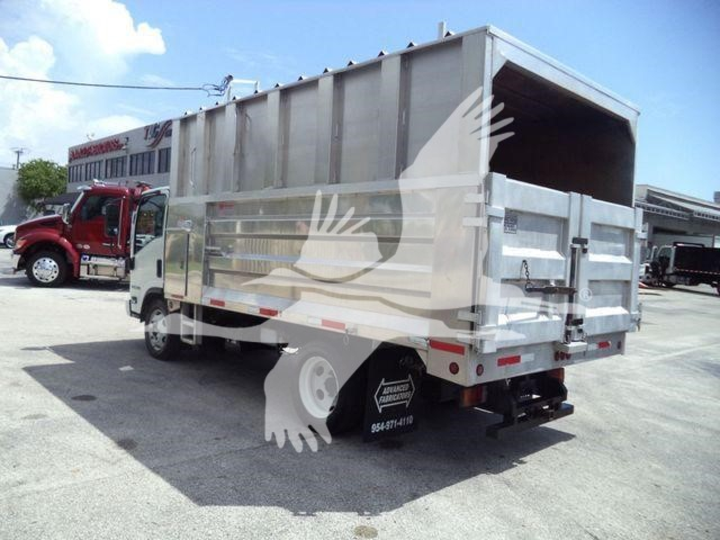 Isuzu NPR/XD truck with a gray dump bed viewed from rear-left side showing cargo bed and tailgate.