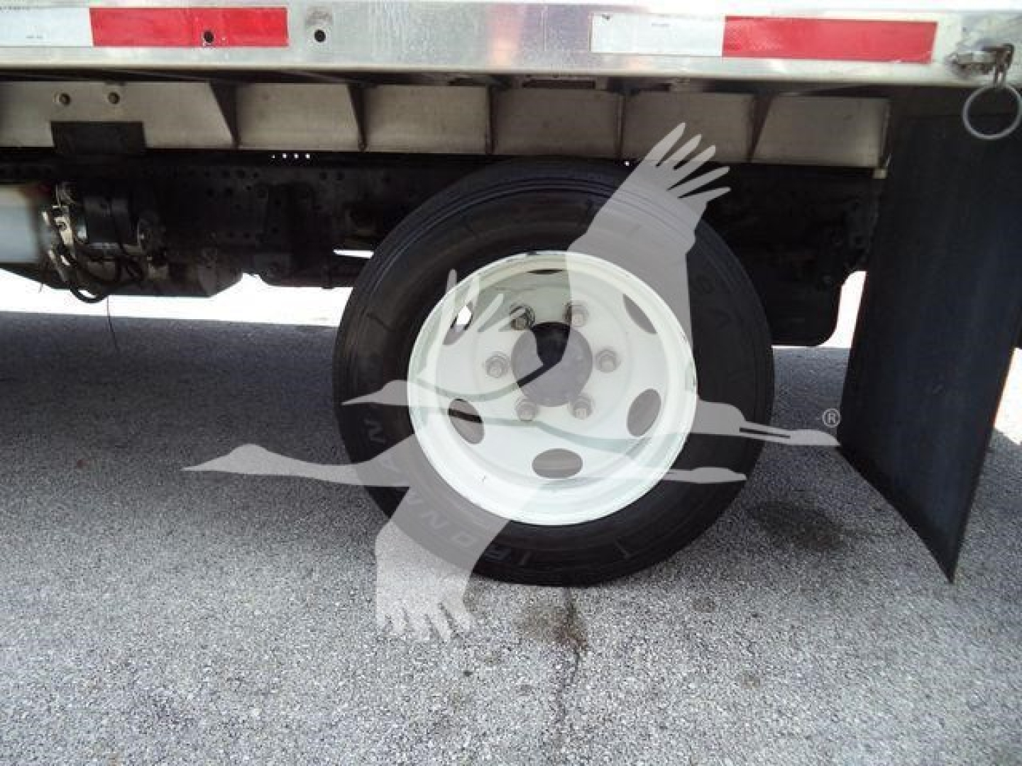 Isuzu NPR XD truck rear wheel and undercarriage showing a white rim and tire under the flatbed.