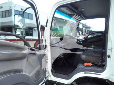 Isuzu NPR XD truck cabin interior view with open driver door showing seating and dashboard.