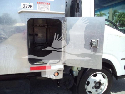 Isuzu NPR XD truck side compartment door open showing storage area and part of wheel; visible label '3726' and hazard sticker on door edge.