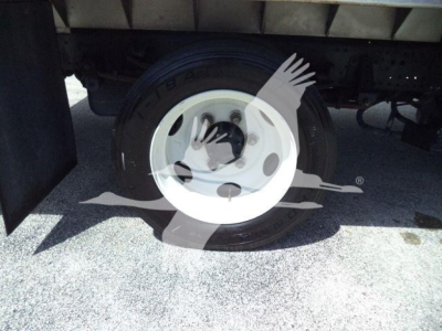 Truck wheel and tire under a Isuzu NPR XD chassis, white steel wheel, black tire, undercarriage visible