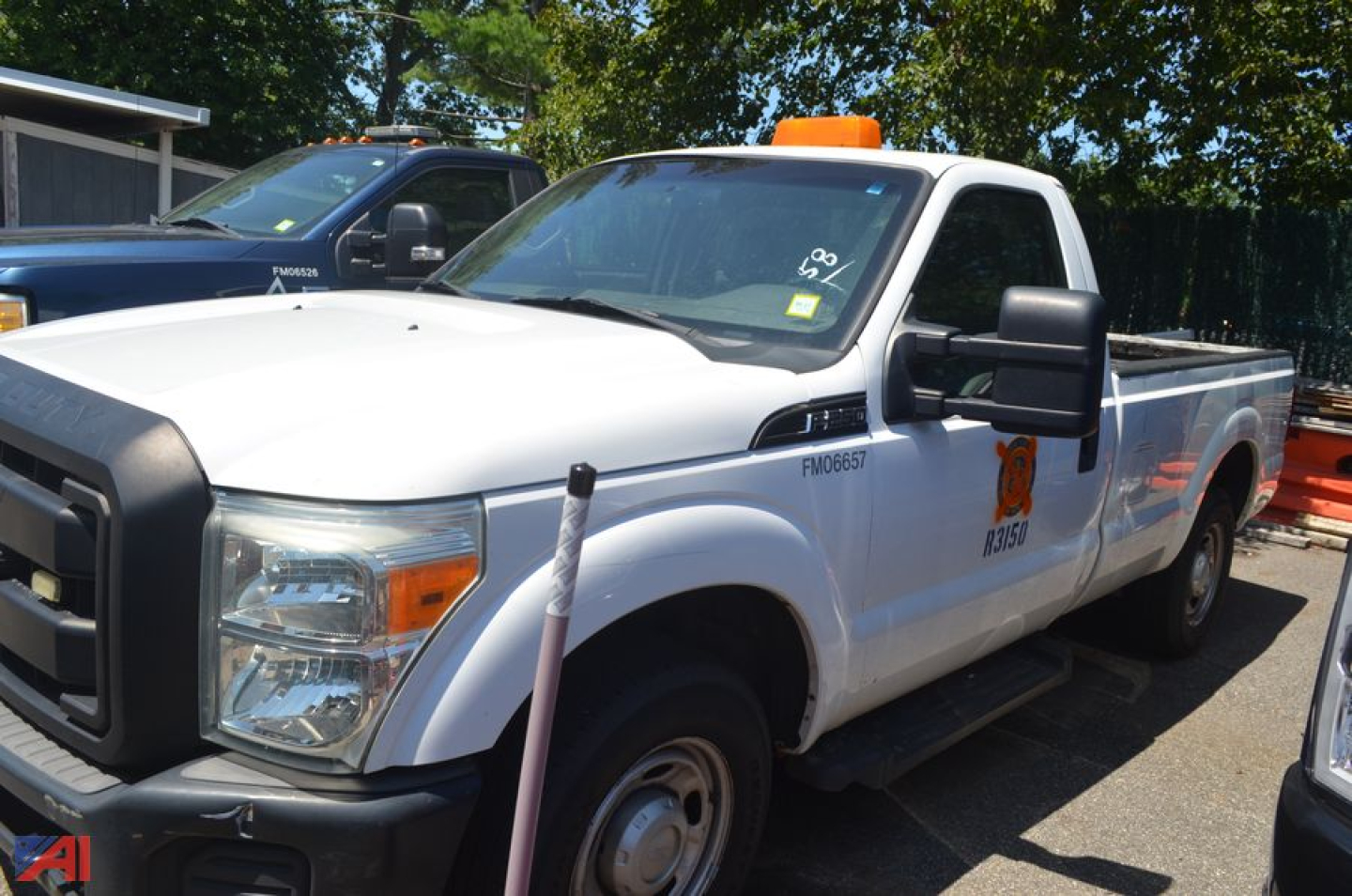 Ford F-250 Super Duty pickup truck in white with utility bed and orange beacon on cab, side view showing front grille and wheel, used vehicle.
