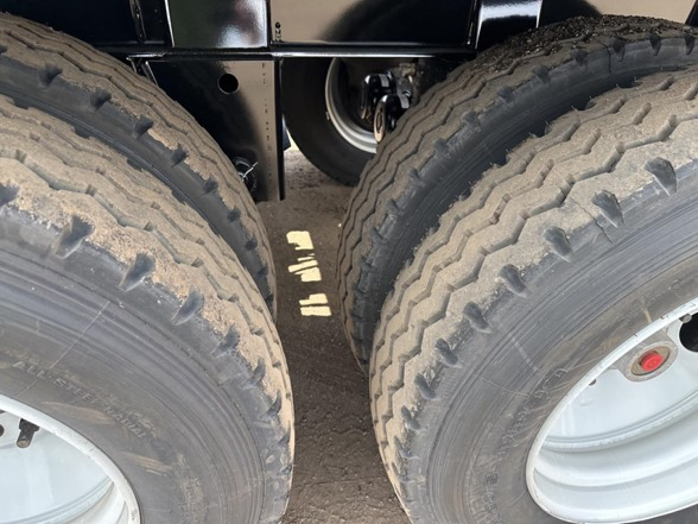 Side view undercarriage of a new Smithco tri-axle air ride side dump trailer showing dual rear tires and suspension area.