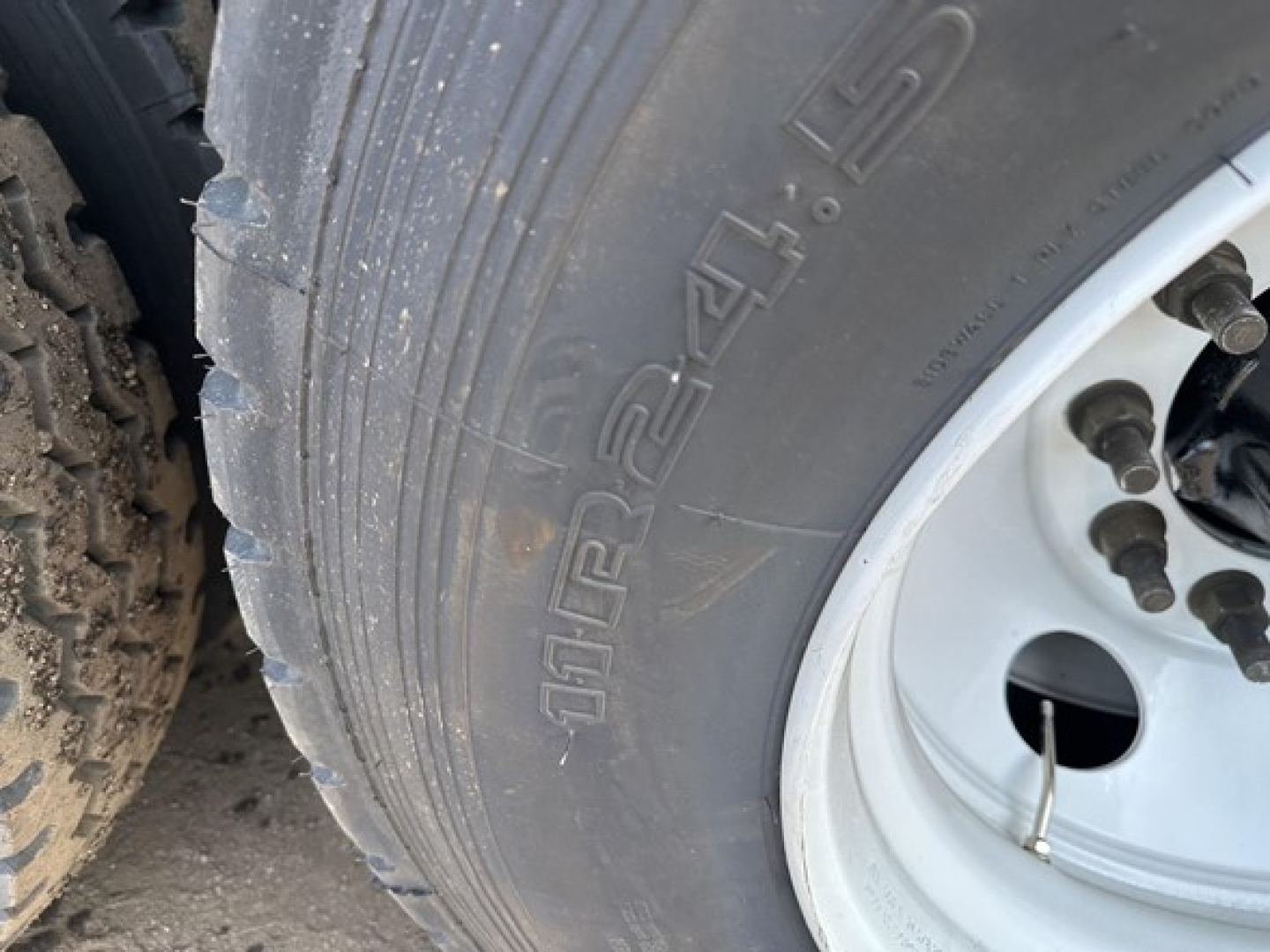 Trailer wheel close-up showing tire markings and wheel hub on a new Smithco tri-axle air ride side dump trailer.