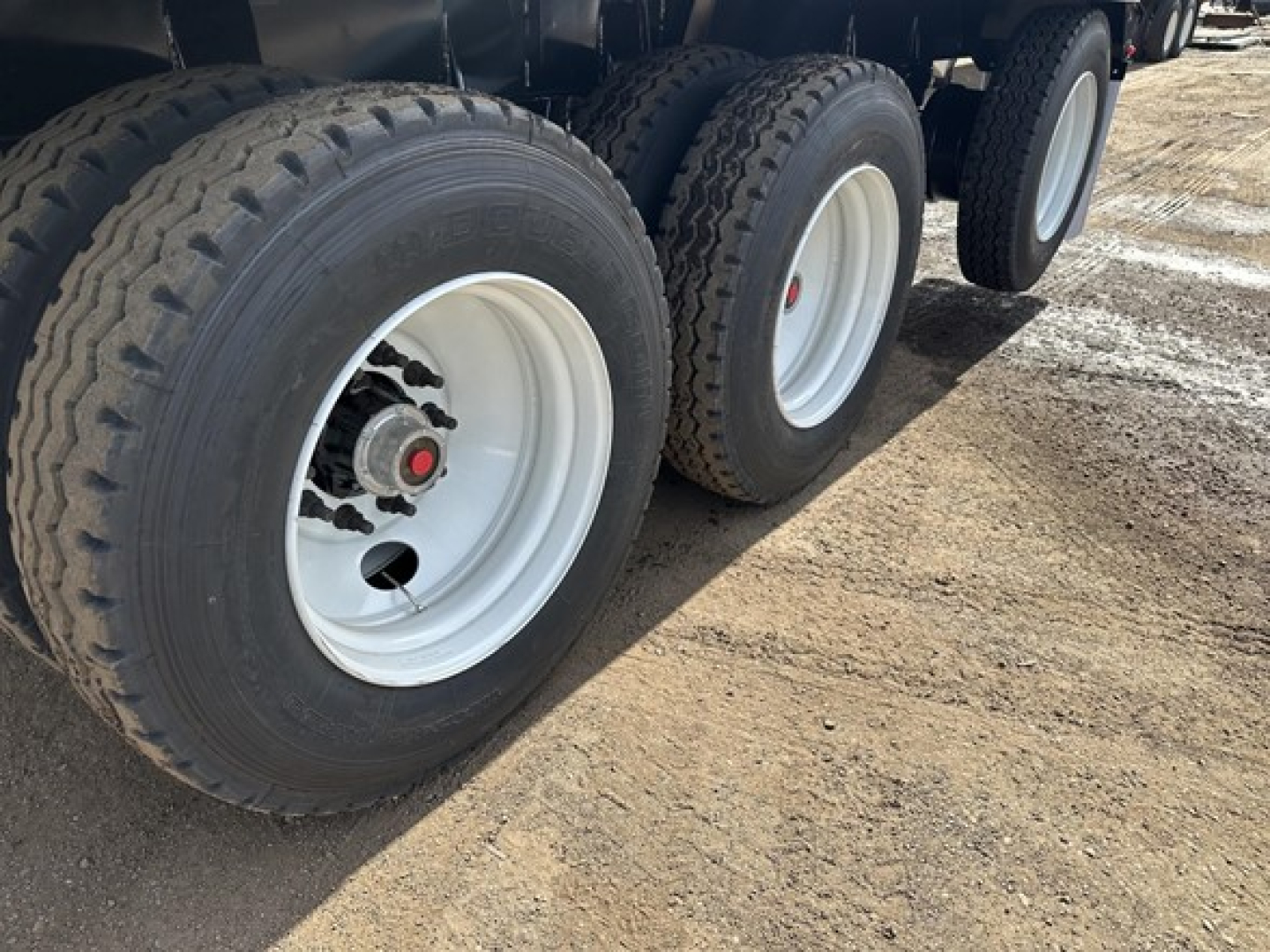 Three axle trailer wheel assembly with white rims and black tires, side view showing dual tires on each axle