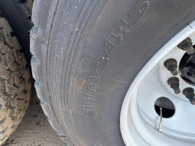 Truck trailer tire close-up with Rim showing tread and stamped text; visible tire brand and wheel bolts.