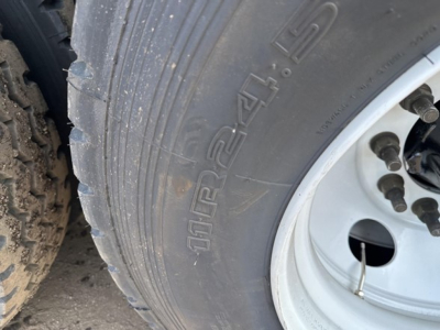Trailer wheel close-up showing tire markings and wheel hub on a new Smithco tri-axle air ride side dump trailer.
