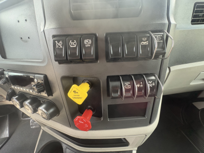 Peterbilt 579 dash panel showing switches, yellow and red trailer brake knobs, and control buttons.