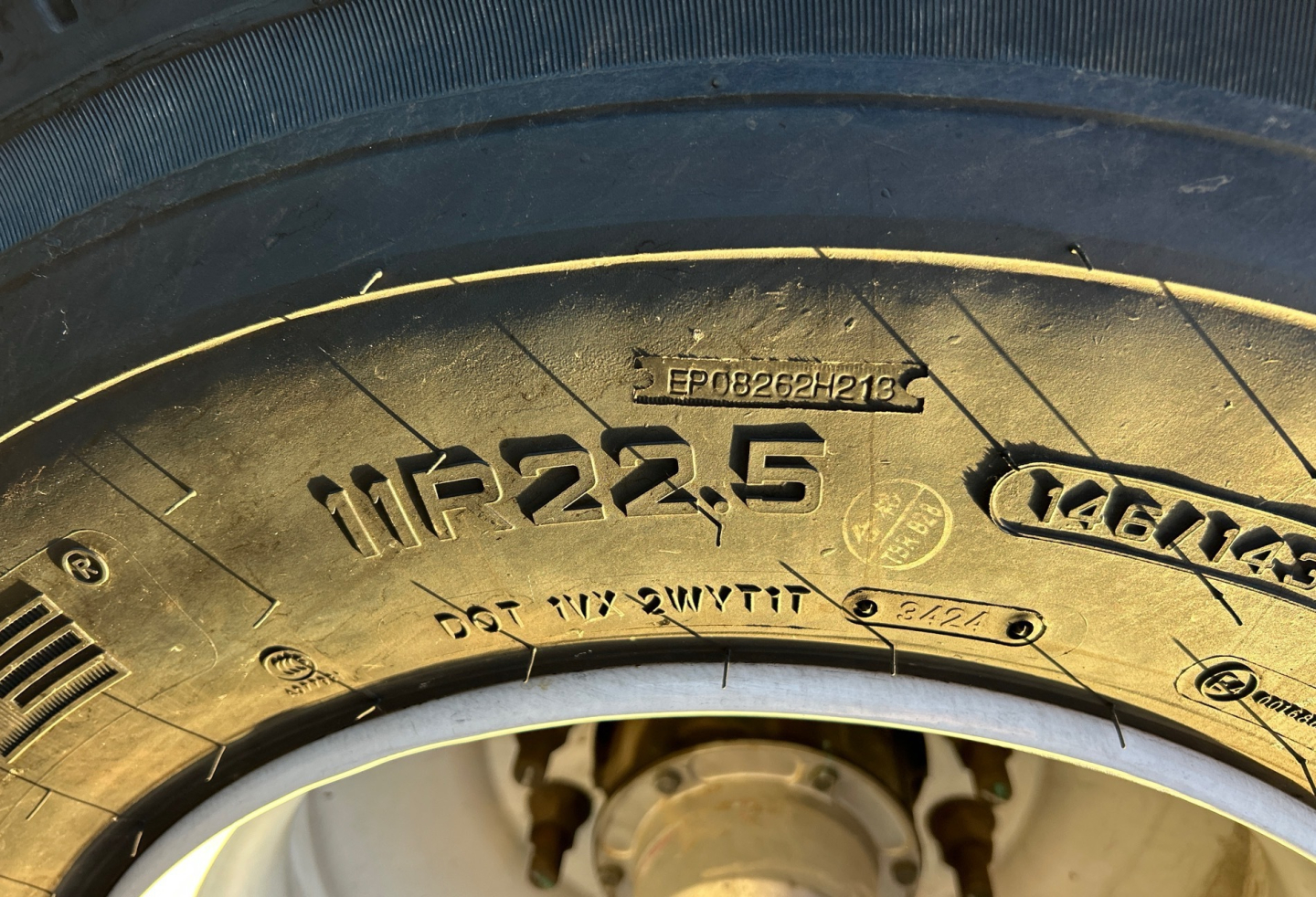 Tire showing embossed markings: 11R22.5 tire size, wheel hub and metal components visible.