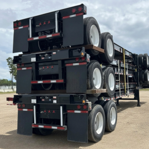 Trailer chassis with stacked intermodal container chassis, showing multiple axles and wheels, black paint, with red and white reflective tape.