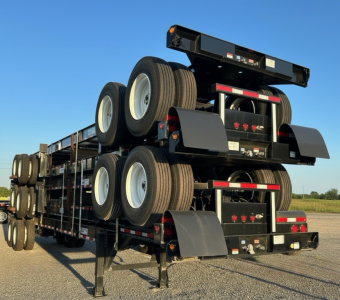 Trailer chassis with dual axle wheels and extendable deck showing tires and undercarriage components.