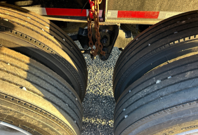 Intermodal container chassis showing dual rear axles with multiple wheels and a central chain hitch.