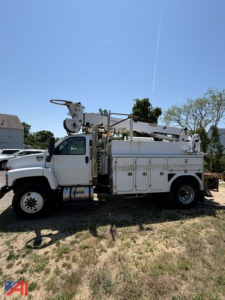 Digger truck with boom lift on a GMC C8500 chassis showing service compartments on the side and extendable crane in an outdoor lot.
