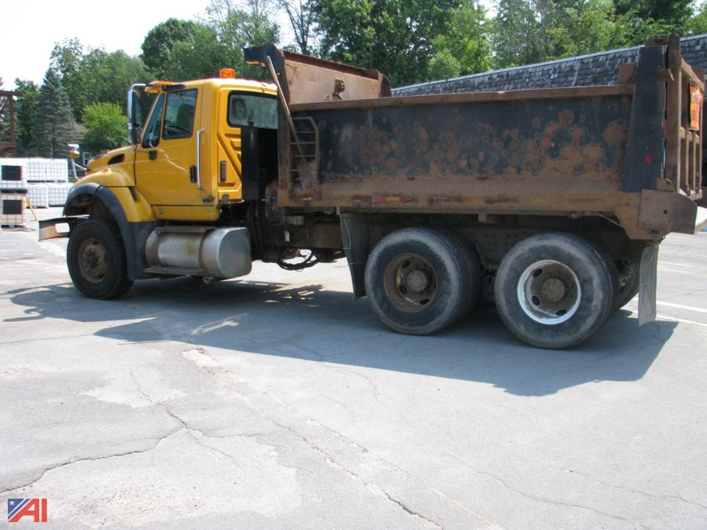 Dump truck showing side view with yellow cab and metal dump bed.