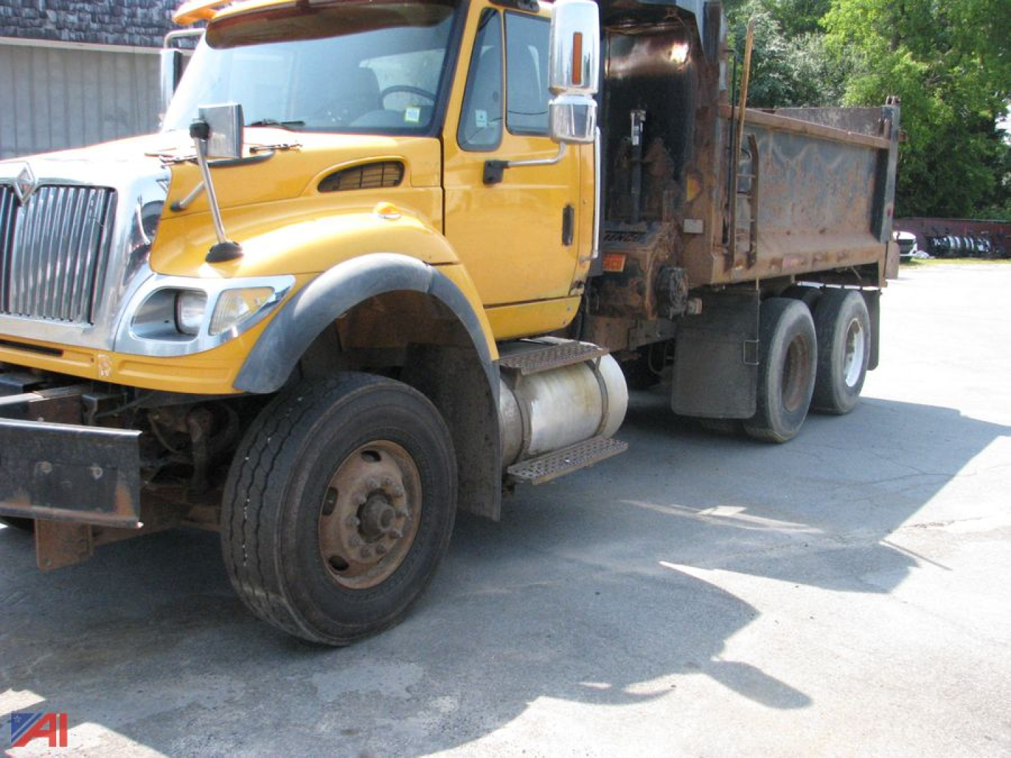 Large yellow International SF547 WorkStar dump truck in service position showing front grille, cab, driver-side door, and open dump bed with mud and dirt.