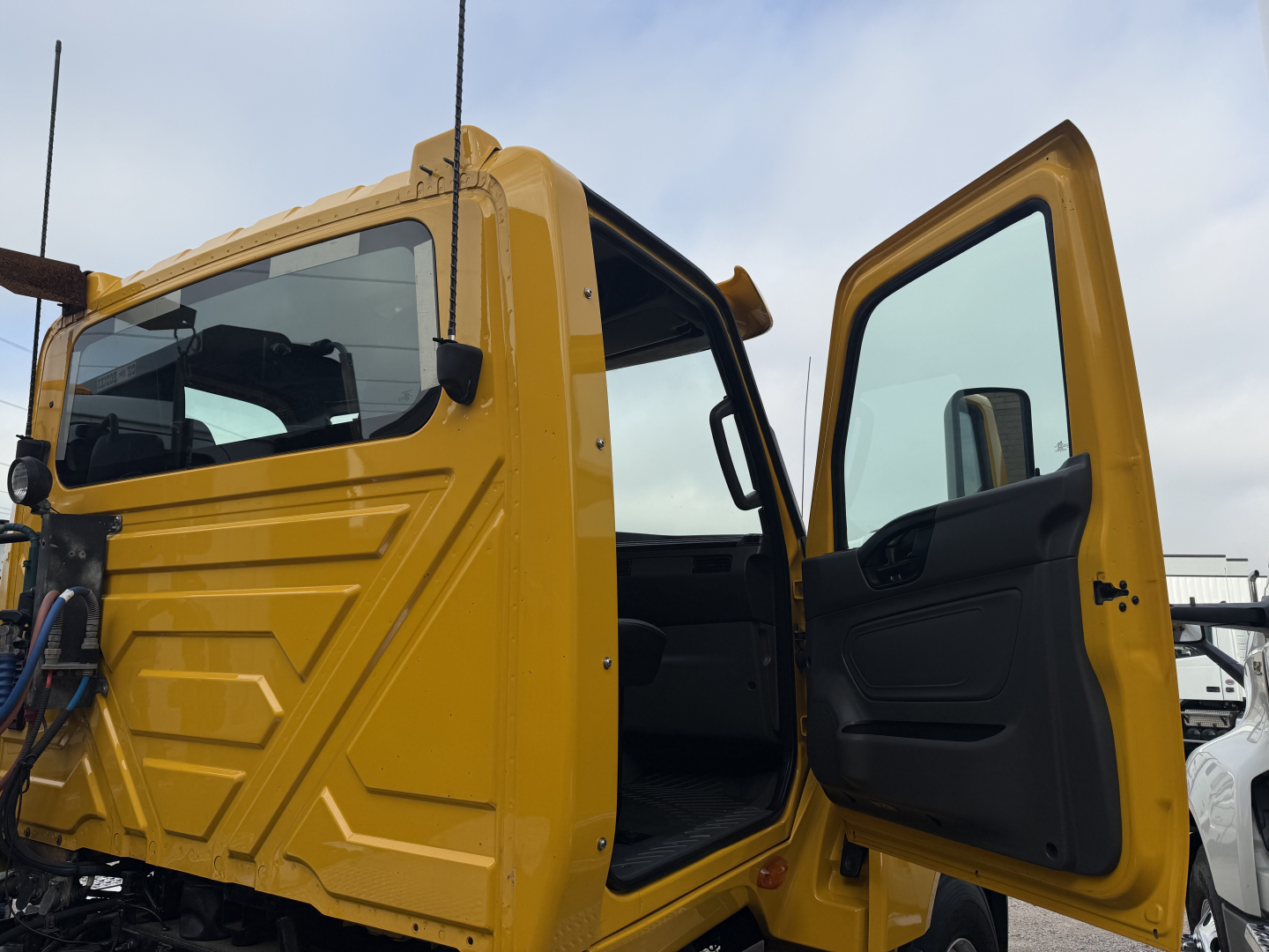 Cab of a yellow 2019 International LT daycab with driver door open; visible VIN 3HSDZTZR1KN729023 and stock number B3111P; part of a trucks lot.