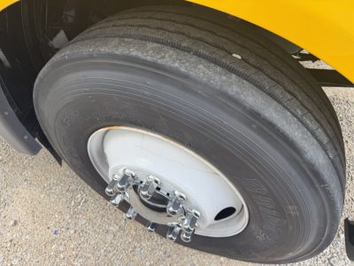 Truck wheel and tire close-up on a yellow International LT, showing a dual rear wheel setup with a large steel rim and lug nuts.