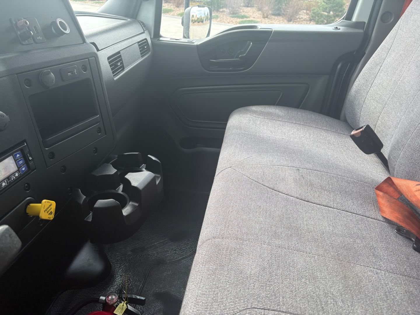 Interior of a 2021 International MV607 cab showing front bench seat, dashboard controls, cup holders, and door panel.