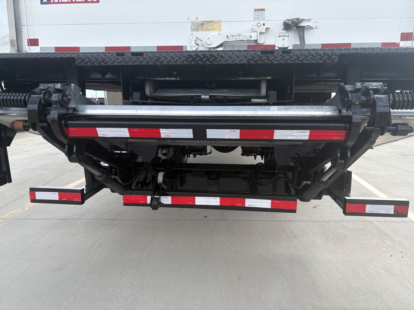 Rear view of a 2021 International MV607 refrigeration truck showing the undercarriage, rear bumper, and crossbars with reflective striping.