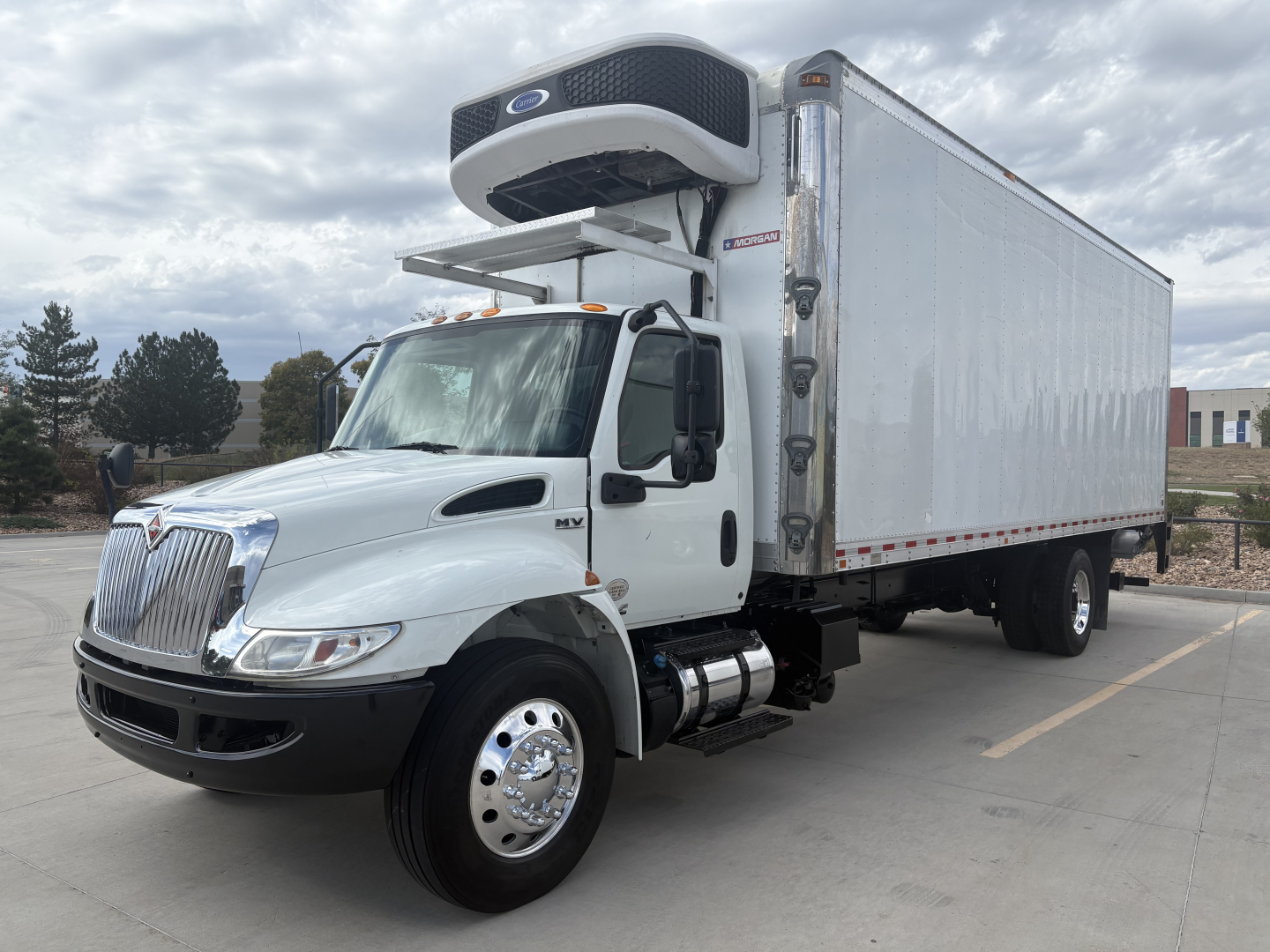 International MV series refrigerated truck showing cab and box with Carrier/Vent cooler unit on top, side mirror, dual rear wheels, and front air dam.