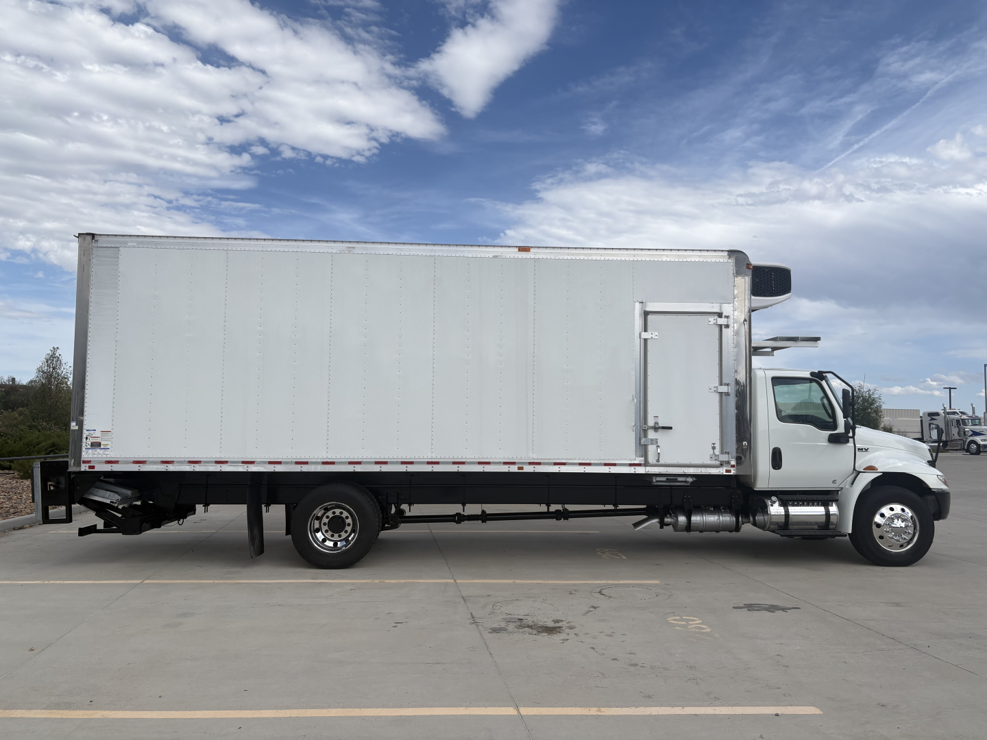 Truck side view of a 2021 International MV607 refrigerated truck showing a large box trailer with white exterior and cab at right.