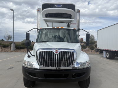 Truck front view with refrigerated unit on cab roof, International MV series grill, headlights, large chrome grille, white cab, stock number 0631113