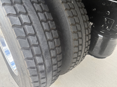 Truck rear dual tires and undercarriage components showing heavy tread tires and a black cylindrical component, part of the drivetrain or suspension on a refrigerated 2021 International MV607.