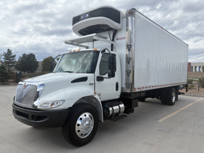 International MV series refrigerated truck showing cab and box with Carrier/Vent cooler unit on top, side mirror, dual rear wheels, and front air dam.