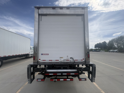 Rear view of a 2021 International MV607 refrigerated truck with roll-up cargo door and rear underride guard, in a parking lot.