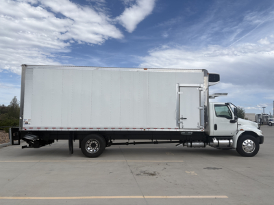 Truck side view of a 2021 International MV607 refrigerated truck showing a large box trailer with white exterior and cab at right.